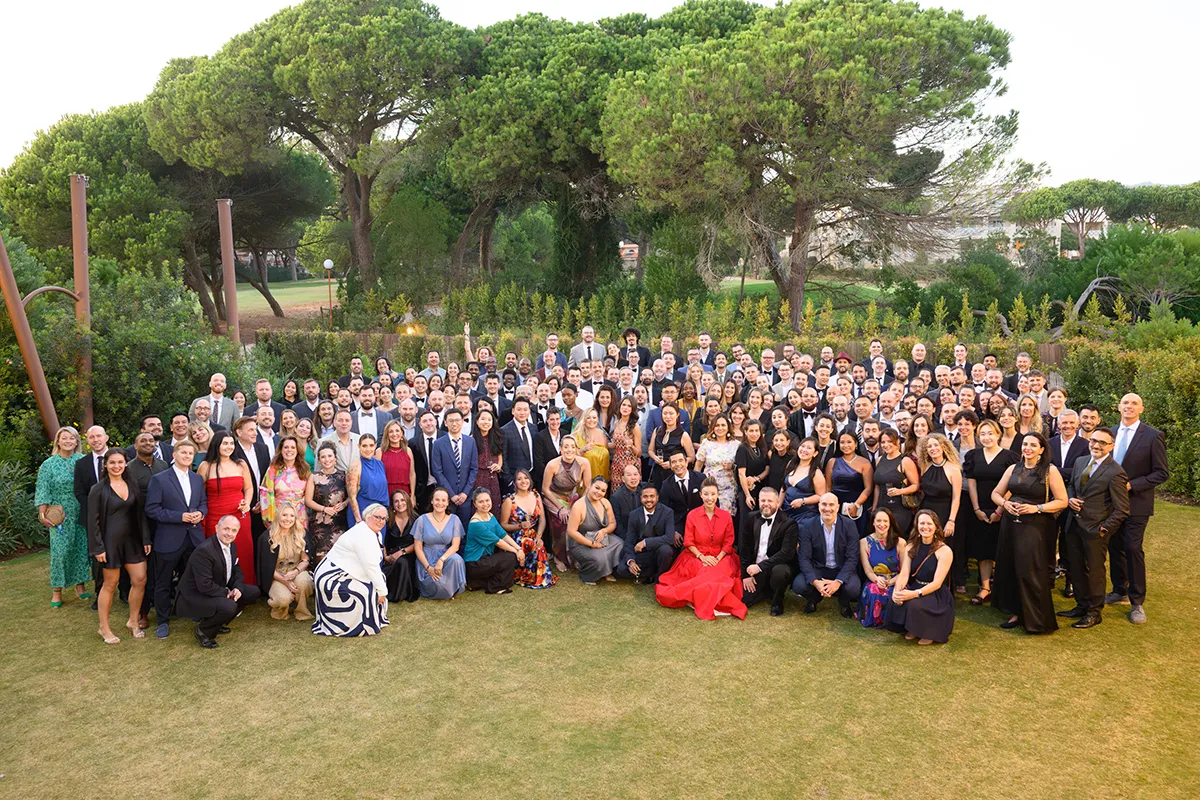 Fotografia de grupo de grande escala com mais de 150 pessoas num jantar de gala corporativo em Lisboa. Todos os colaboradores em traje formal a celebrar, com iluminação de evento premium.